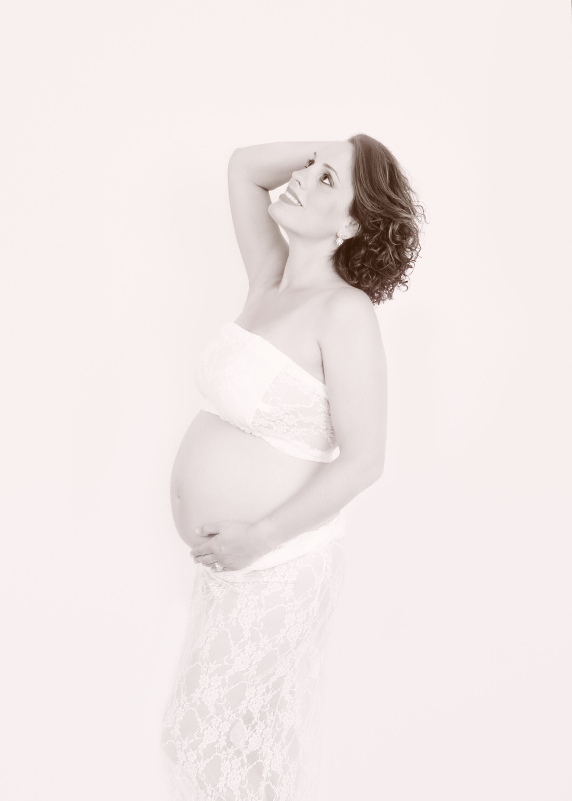 maternity photoshoot with mom to be in a white halter top and lace skirt.