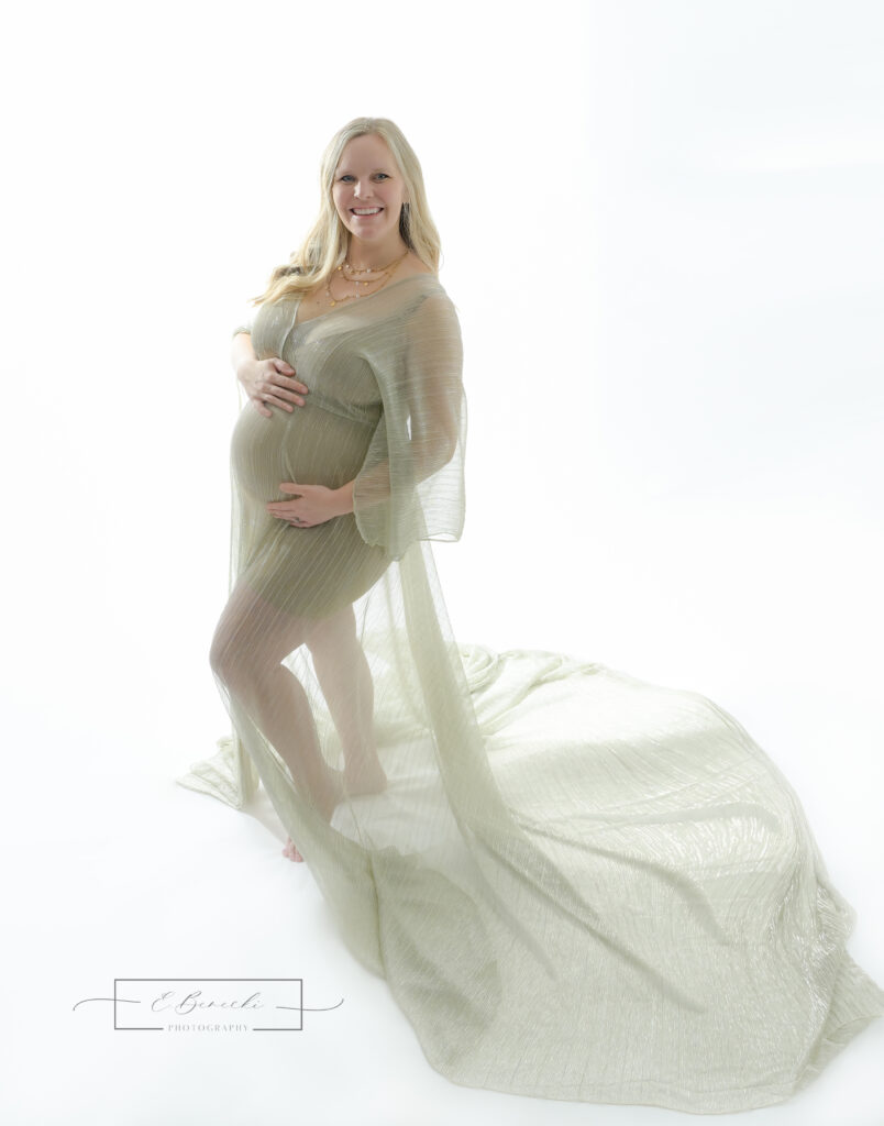 Bainbridge Island maternity photo session with mom to be wearing a sheer golden gown against a backlit white background.