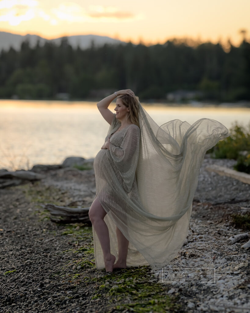 Bainbridge Island beach maternity photo session with mom to be wearing a gold flowing gown blowing in the gentle breeze.