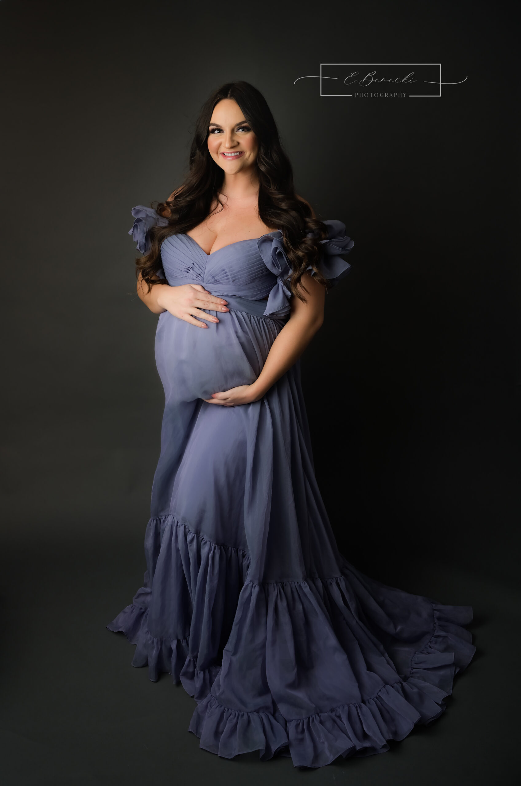 Mom to be wearing a chiffon purple flowing dress for her studio pregnancy photo session.